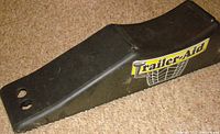 Side angle view of the black Trailer-Aid ramp showing shape and sticker on the side.