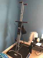 Front view of Maxi Climber standing on black floor mat near blue wall and other furniture.
