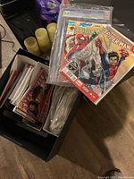 Box containing a collection of comic books featuring various superhero characters such as Spider-Man, Superman, Smallville, Dark Hawk, and Punisher.