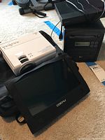 Photo displaying Vankyo projector, LG DVD drive, Sony Blu-ray player stacked, and Coovn portable video player on carpet.