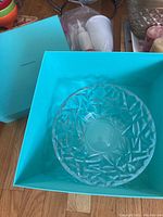 Clear Tiffany & Co. crystal bowl inside Tiffany blue box on wood floor, showing interior and geometric cut design.