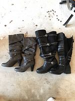 Two pairs of women's riding boots placed on the floor side by side, showing overall appearance and style comparison.