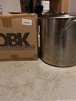 Photo of the OBK cardboard box labeled OntarioBeerKegs.com alongside the stainless steel brew pot sitting on the floor.