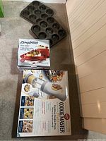 Photo showing all items in the lot: Brie Baker box, Wilton Cookie Master Plus box, and two 9-cup muffin trays.