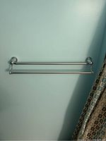 Double towel bar mounted on blue wall with two parallel bars and polished chrome finish