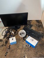Overview of the entire lot including Lenovo monitor, keyboard, USB fan, Blink Mini camera box, and phone holder stand box on floor.
