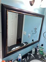 Full view of the rectangular mirror on a bathroom wall above the sink, showing the frame details and surroundings.