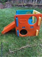 Side view of the colorful plastic toddler slide showing the side panels with circular cutouts and the orange slide attached.