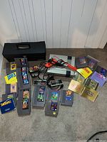 NES console, controllers, Zapper light gun, Game Genie, carrying case and assorted cartridges on carpet