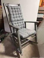 Front angle view of the wood rocking chair showing gray tufted cushions on the backrest and seat.