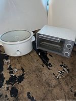 Photo of PC slow cooker and Sunbeam toaster oven together on a stained floor.