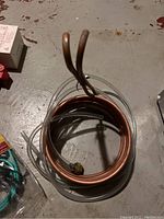 Top-down photo of copper coil wort chiller with attached clear rubber tubing coiled inside