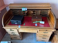 Front view of solid oak roll top desk with tambour top opened to reveal red felt writing surface and pigeonhole compartments