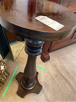 Full view of the wooden display plinth showing the round top and the pedestal base with three-point flat base.
