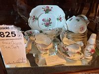 Full view of tea set including teapot, plate, teacups, salt and pepper shakers, and gravy boat arranged on reflective surface