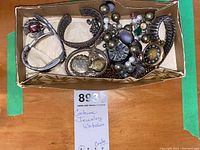 Boxed assortment of watches, bracelets, and necklaces showing multiple pieces including expandable band watch, bead necklaces, and brooches.