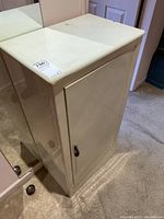 Front angled view of beige metal cabinet showing door closed and scratches on surface.