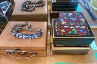 Photo of two wooden decorative music boxes stacked and shell disc necklace on tan leather jewelry case