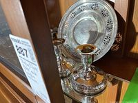 Photo shows two sterling silver candle holders in front of a sterling silver plate with a pierced floral pattern on the edge.