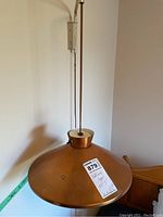 Photo showing the copper lampshade with attached counterweight and suspension rod