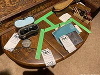 View of the vintage solid oak small folding side table with drop leaves, showing wood grain and some collectible items on the table (not included in sale).