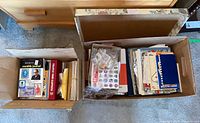 Two cardboard boxes containing journal issues, binder, stamp bags and ephemera viewed from above