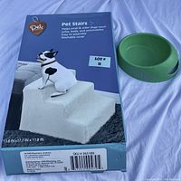 Photo showing boxed Pet Stairs product with washable cover and green dog bowl next to it