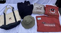 Photo of the entire lot showing tote bag, sweatshirts, T-shirt, quarter zip fleece, and bucket hat with visible dressage-themed logos and text