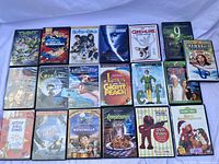 Set of 19 kids DVDs shown on white surface including TMNT, Meet the Robinsons, Hotel for Dogs, Gremlins, Elmo, Elf, and others.