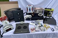 Photo showing all lot items including DVD player, modem, cooling pads, MP3 player, mouse, radio with phone, VTech cordless phone, power strips and various cables.