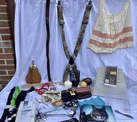 Photo showing knit sleeveless top, camouflage suspenders, leather belt, small purses, decorative wooden cutting board, clear plastic organizers, and other small household items