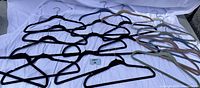 Overview of 20 velvet hangers in black and various pastel colors laid out on a white cloth background.