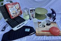 Entire lot displayed together including waffle maker, chopper, French press, personal blender, Chef Basket, olive oil dispenser and miscellaneous accessories.