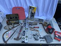 Wide view of workshop tools laid out on a surface: saws, hammer, spirit levels, toolbox, and hardware.