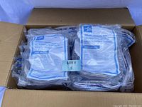 Photo showing an open cardboard box containing multiple individually packaged urinary drainage bags with visible 2000 ml markings and blue printed labels.