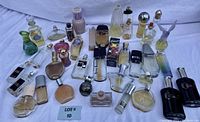 Photo showing full lot of 31 various vintage perfume bottles on a white cloth background, assortment of styles, colors and brands.
