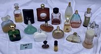 Photo of 17 assorted vintage perfume bottles in various shapes and colors arranged on a white cloth.