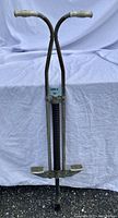 Front view of the vintage pogo stick with metal frame, spring, and rubber handle grips.