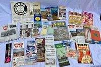 Top-down photo of an array of vintage travel brochures, maps, books, and stickers spread out on a surface.
