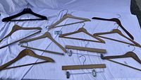 Wide shot of all hangers with white backdrop, showing 11 hangers in total including flat, curved, pants with clips, and one black plastic hanger