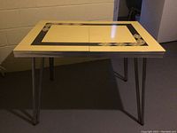 Side view of Arborite table showing cream laminate top with black geometric patterned border and foldable seam down center