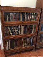 Frontal view of entire three-section wooden barrister bookcase showing glass front doors and loaded shelves
