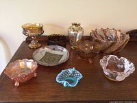 Lot of assorted carnival glass and decorative items including various bowls and ceramic plate on a wooden surface