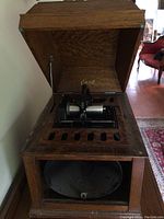 Wooden cabinet with hinged top open showing internal phonograph mechanism and lower resonator compartment