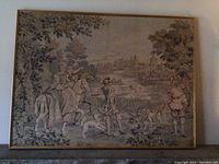 Full view of the framed cloth material artwork showing a group of three people in historical attire outdoors with a dog and distant castle scenery.