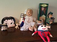 Full lot showing large vintage baby doll, Betty Boop collectibles, Humpty Dumpty plush, boxed porcelain doll, and smaller figures