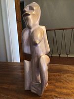 Front and 3/4 angle view showing stylized abstract wooden human figure with rounded chest and angular face. Light-colored wood grain finish visible.