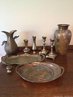 Overview of all yellow brass items showing vases, trays, candlesticks, and a small round piece.