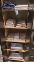 Full view of entire shelving unit with five shelves of folded bed linens in various colors and some packaged sets.