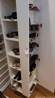 Overview of shelving unit holding multiple belts and two pairs of slide sandals